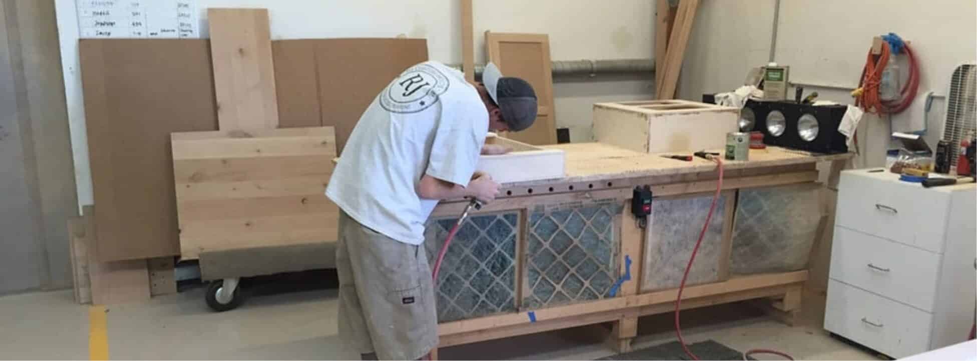 craftsman-assembling-wood-cabinet-pieces-in-the-production-workshop AZ Cabinet Maker workshop with professional woodworking machinery