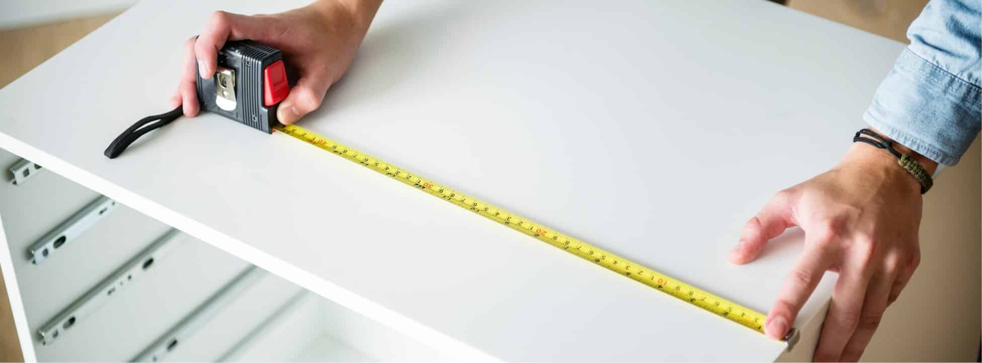 craftsman-measuring-and-marking-a-melamine-panel-for-custom-cabinets Craftsman measuring and marking a melamine panel for custom cabinets